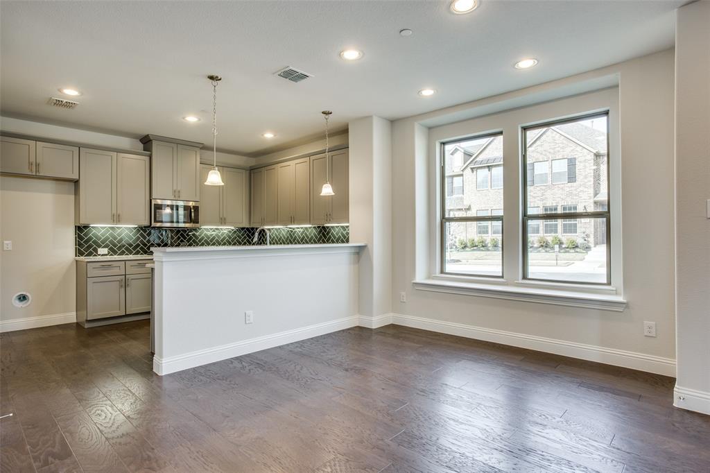 Kitchen featuring wood-finish flooring, shaker-style cabinetry, a herringbone-patterned tile backsplash, pendant lighting, and a peninsula breakfast bar Kitchen featuring wood-finish flooring, shaker-style cabinetry, a herringbone-patterned tile backsplash, pendant lighting, and a peninsula breakfast bar