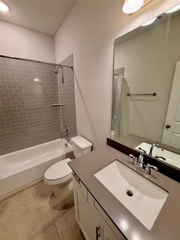 Bathroom featuring a vanity with a solid-surface countertop and integrated basin, gray subway tile shower surround, polished chrome fixtures, and ceramic tile flooring Bathroom featuring a vanity with a solid-surface countertop and integrated basin, gray subway tile shower surround, polished chrome fixtures, and ceramic tile flooring