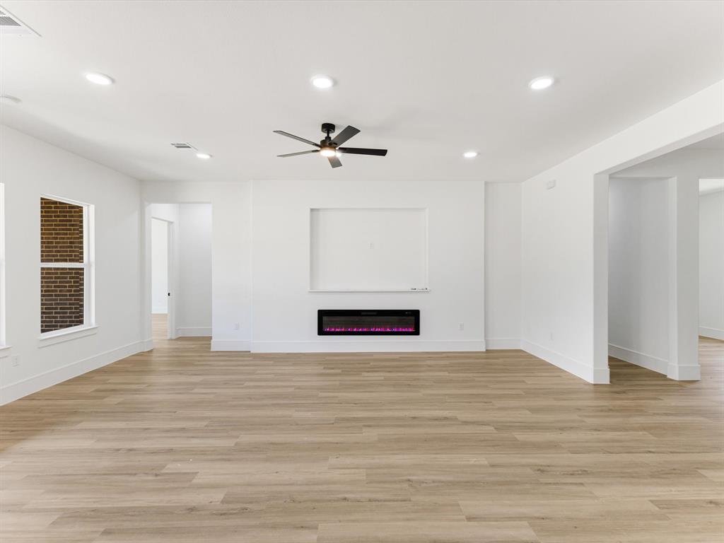 Interior featuring wood-finish flooring, recessed lighting, a ceiling fan, a built-in electric fireplace, and a recessed wall niche