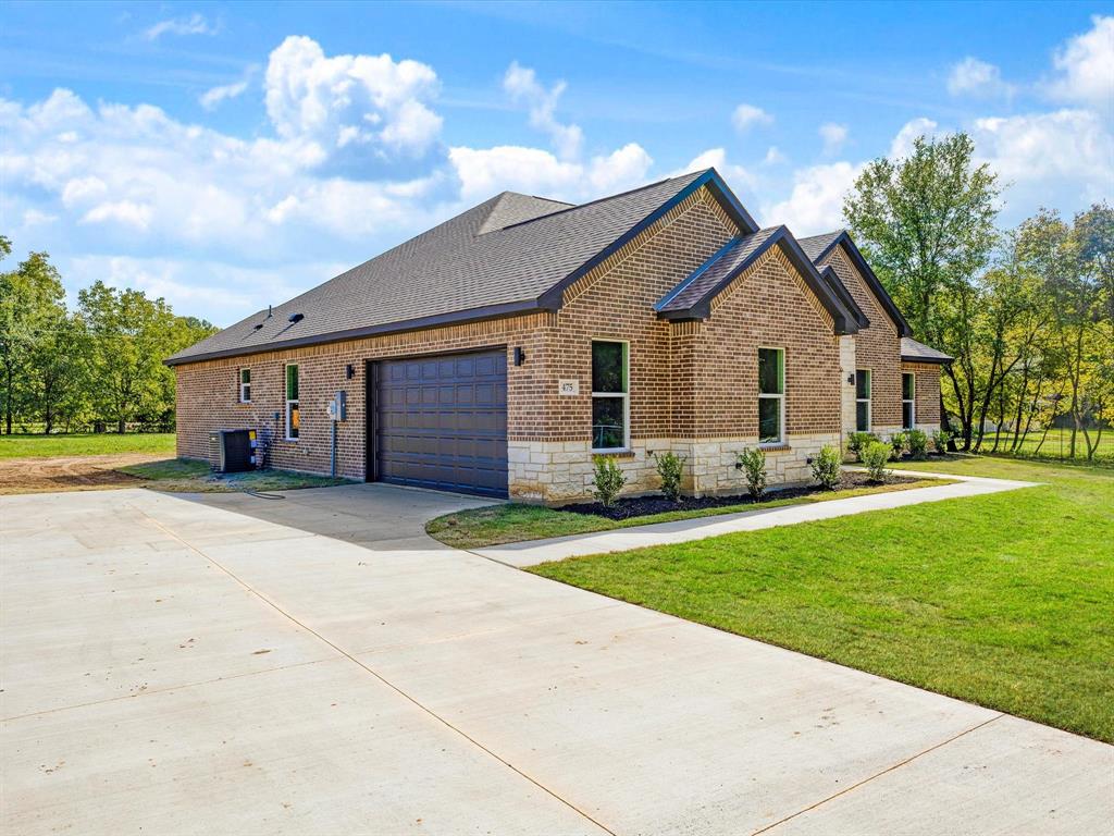 Single-story brick exterior featuring a multi-gabled roofline, stone veneer accents, an attached two-car garage, and concrete driveway