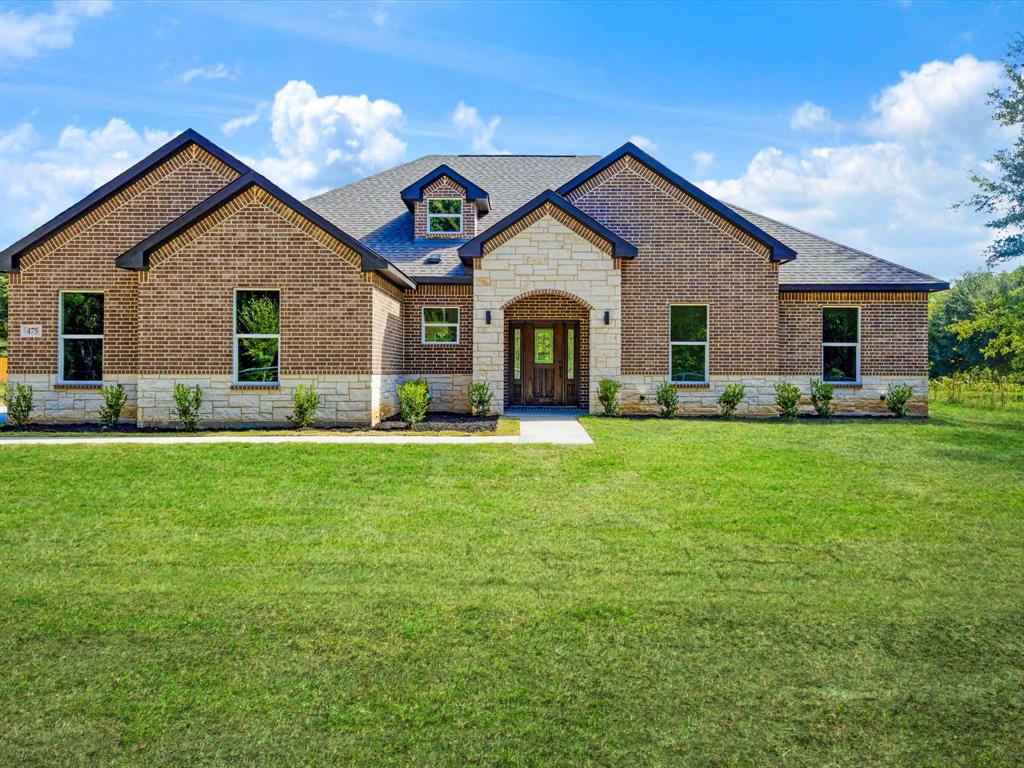 Brick and stone masonry exterior with a prominent arched stone entryway, multi-gable roofline, and dormer window