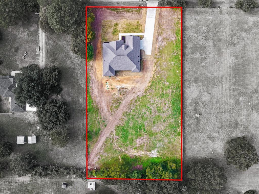Aerial perspective of a detached residential structure featuring a multi-gable roof, concrete driveway, and expansive lot