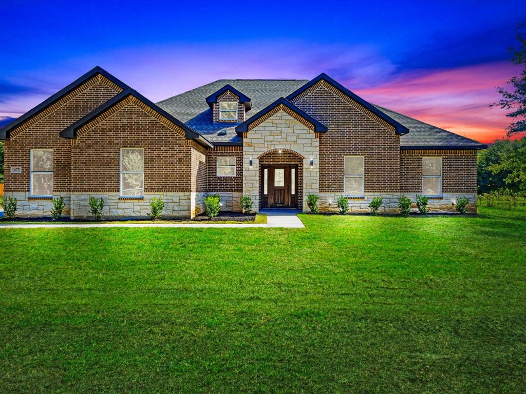 Brick and stone facade featuring a gabled roofline, arched entryway, and multi-pane front door