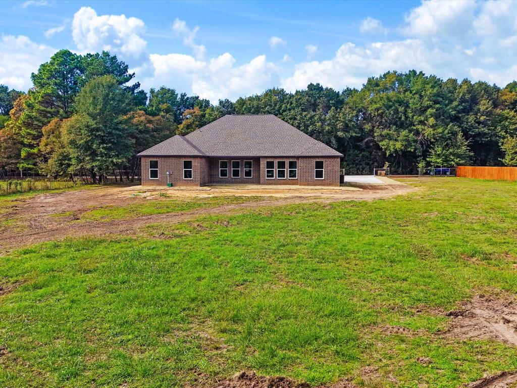 Single-story brick exterior featuring a hip roof, multi-pane windows, and an expansive rear acreage lot