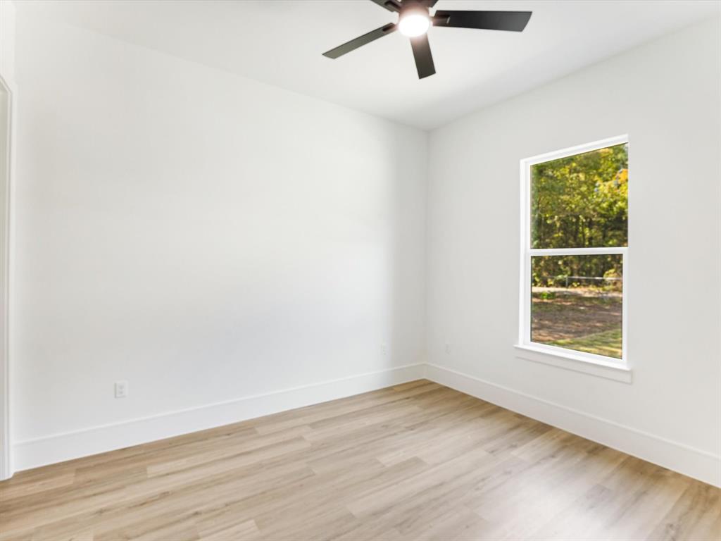 Neutral-toned wall finish, wood-finish flooring, single-hung window, and a matte black ceiling fan with an integrated light fixture