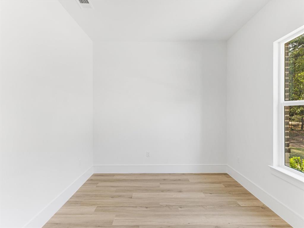 Neutral interior space featuring crisp white walls, wood-finish flooring, and a single-pane window