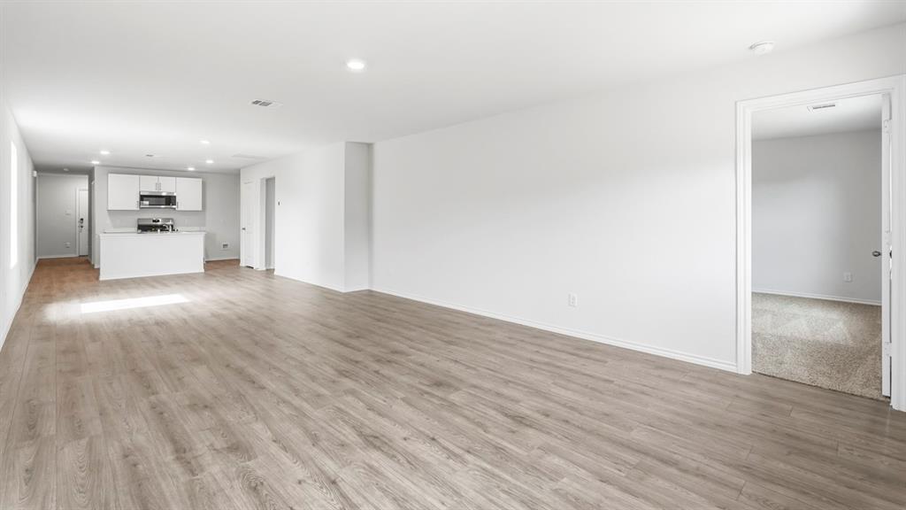 Spacious living area with wood-finish flooring, recessed lighting, and a white color palette