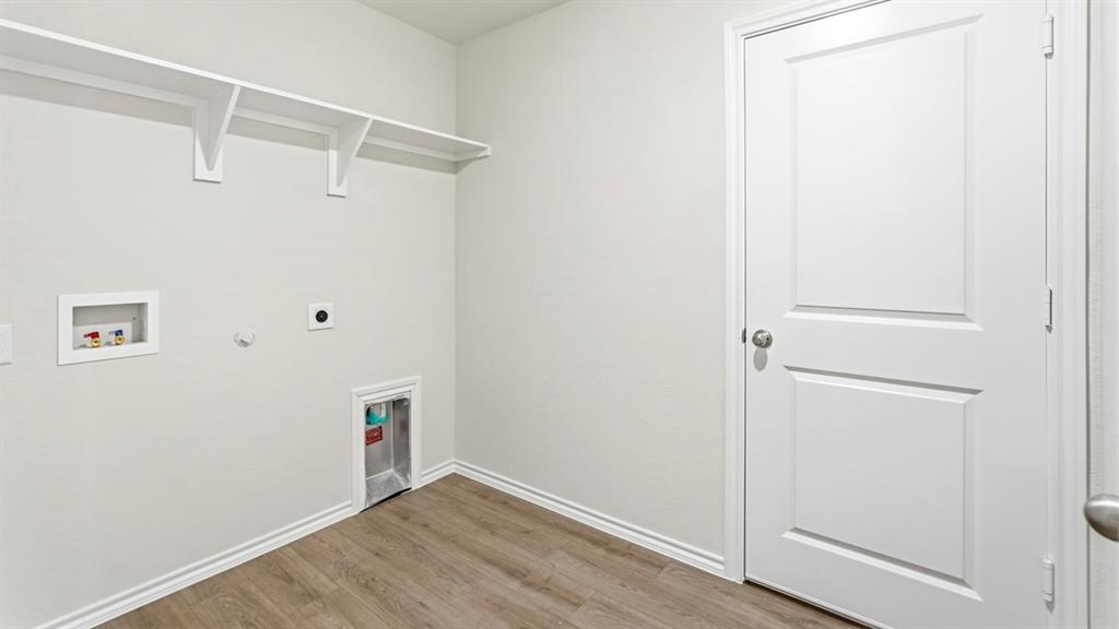 Utility space featuring wood-finish flooring, white walls, and built-in shelving