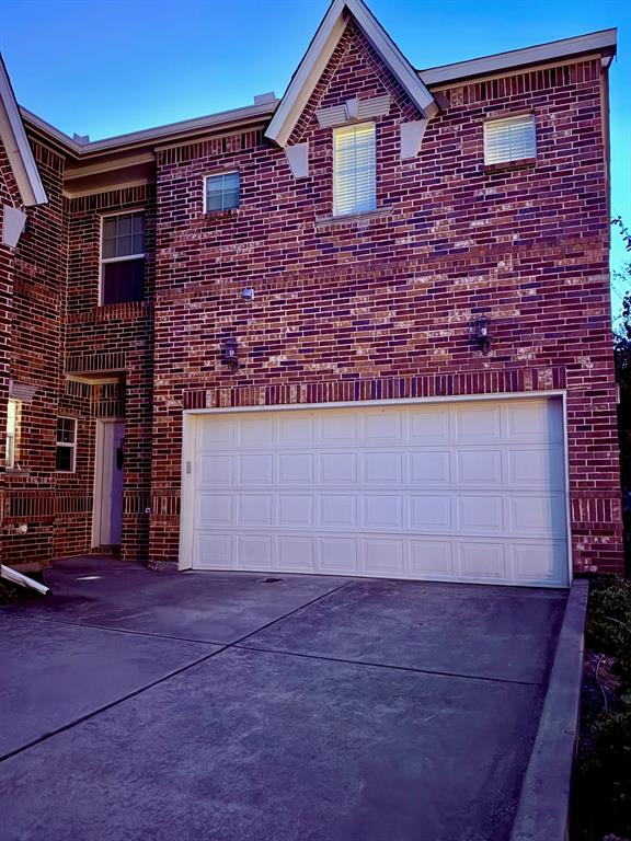 Multi-story brick exterior featuring a multi-gabled roofline, double-pane windows with grid detailing, and a two-car garage with a paneled door Multi-story brick exterior featuring a multi-gabled roofline, double-pane windows with grid detailing, and a two-car garage with a paneled door