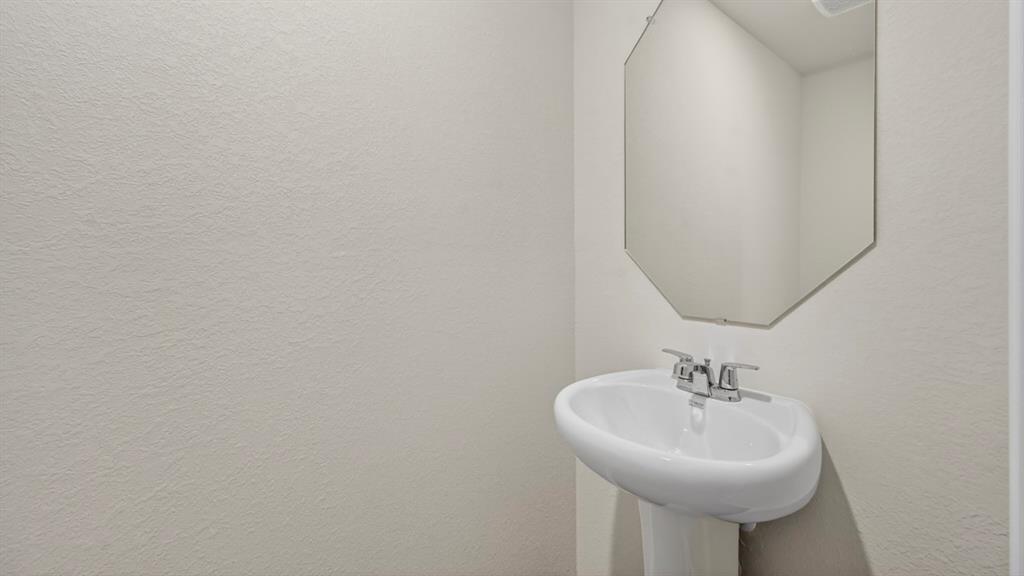 Pedestal sink with chrome faucet and an octagonal wall-mounted mirror