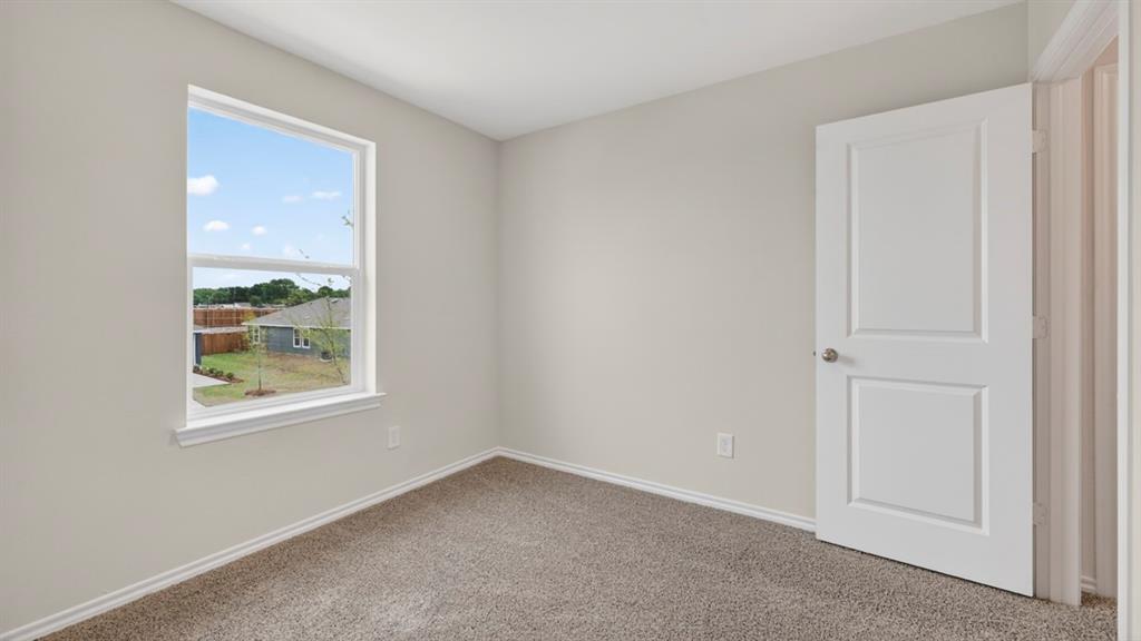 Room featuring a window with white trim, light gray walls, and textured carpet flooring