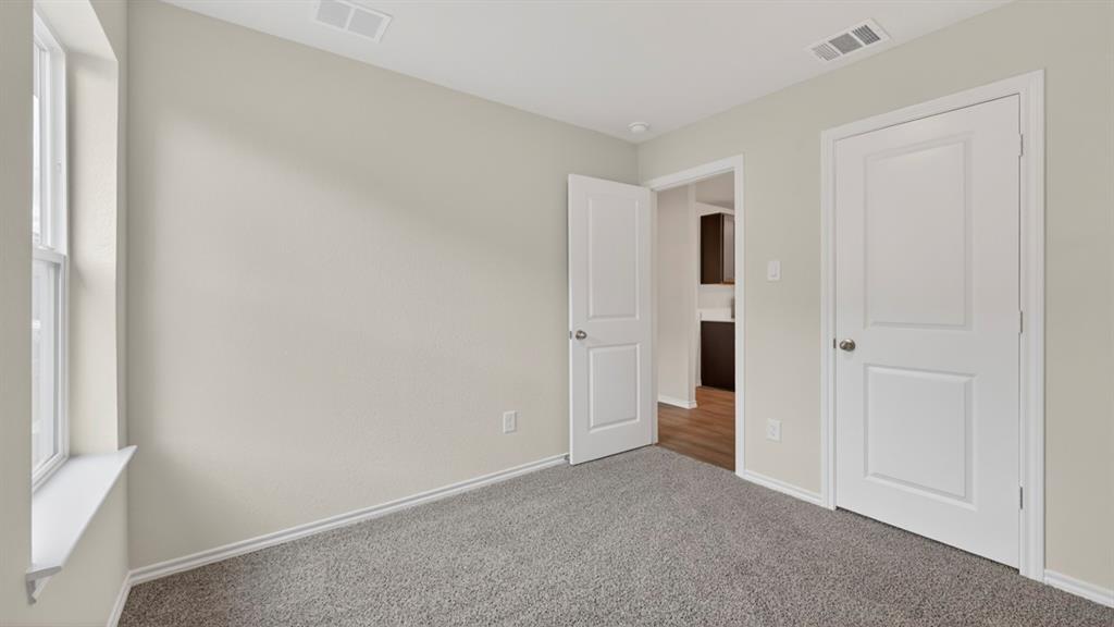 Light gray walls, window with white trim, gray carpet, and white two-panel doors