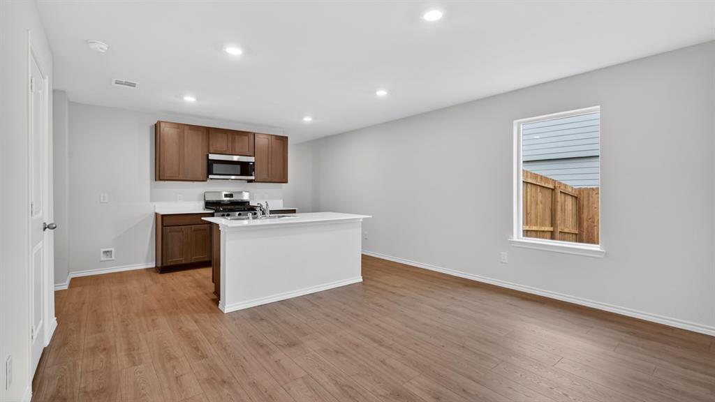 Open-concept layout with wood-finish flooring, recessed lighting, and a kitchen island Open-concept layout with wood-finish flooring, recessed lighting, and a kitchen island