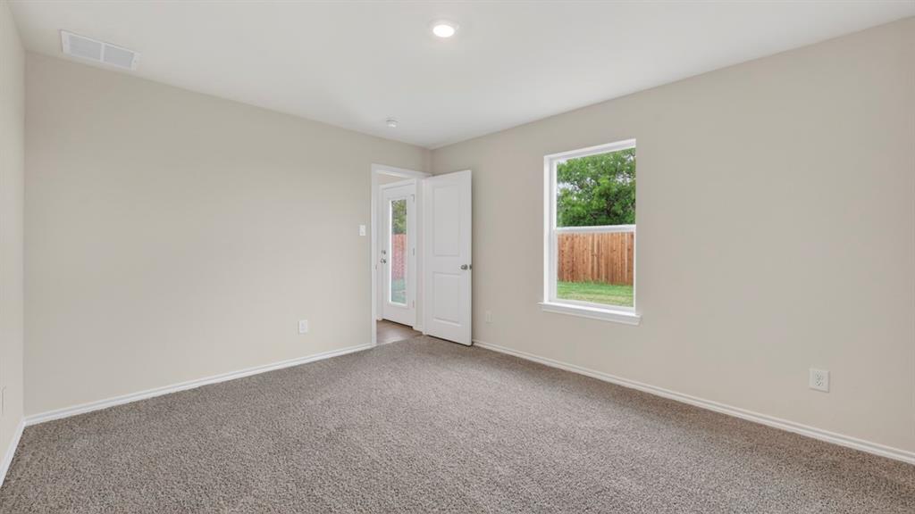 Neutral wall paint, carpet flooring, a window with exterior visibility, and a solid door with a frosted glass panel