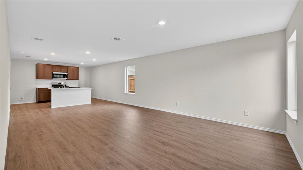 Open-concept living space featuring wood-finish flooring, recessed lighting, and a kitchen island with a white countertop