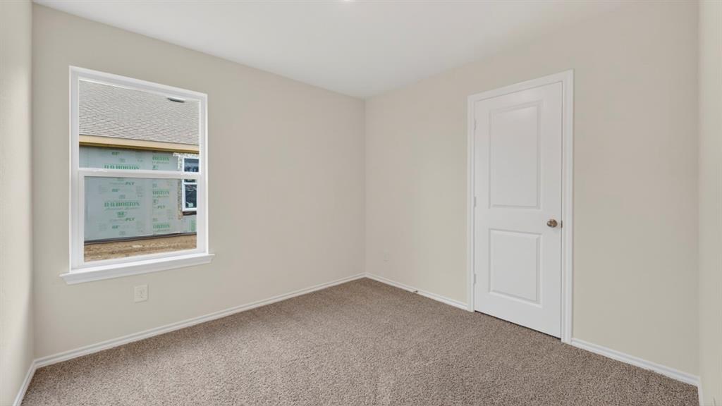 Neutral-toned carpeting, white interior door with polished hardware, white trim, and a white-framed window