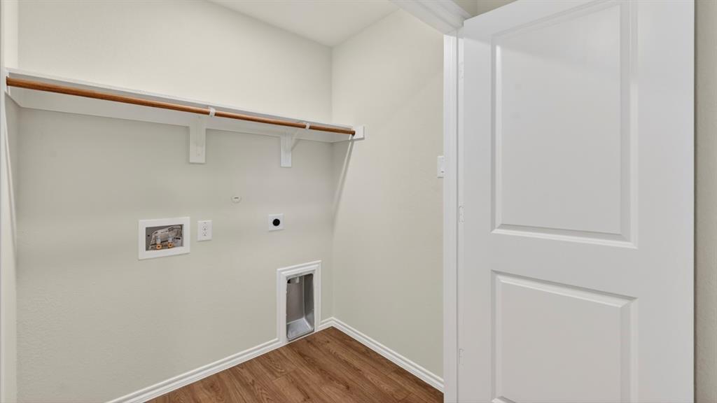 Laundry area featuring wood-finish flooring, a built-in shelving unit, and a white paneled door Laundry area featuring wood-finish flooring, a built-in shelving unit, and a white paneled door