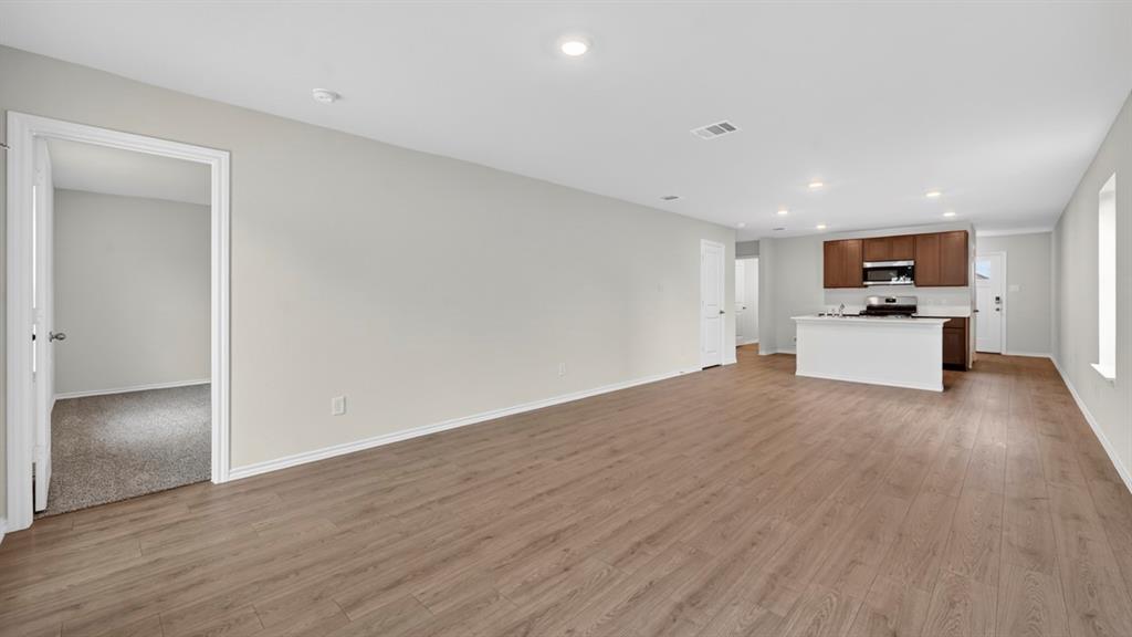 Open-concept living area featuring wood-finish flooring, recessed lighting, and a kitchen island with white cabinetry