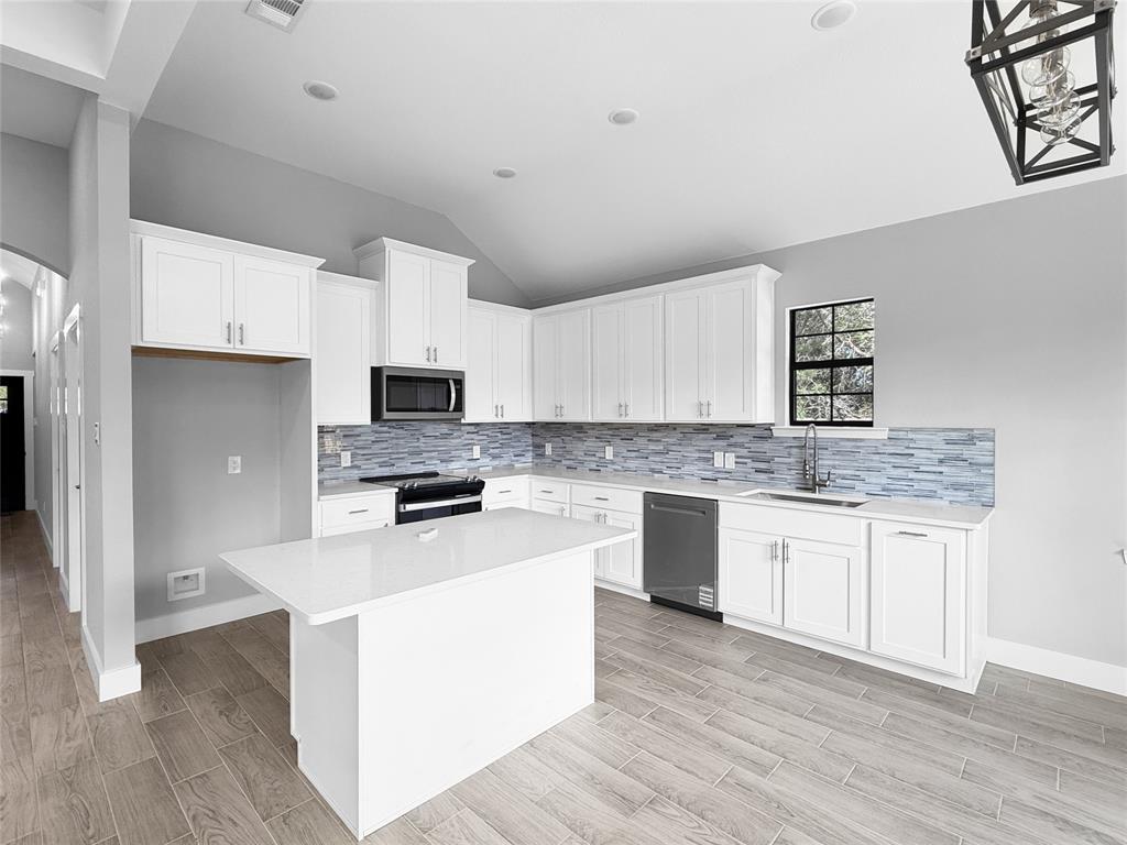 Kitchen featuring white shaker-style cabinetry, quartz countertops, multi-tonal linear tile backsplash, wood-finish flooring, and a center island Kitchen featuring white shaker-style cabinetry, quartz countertops, multi-tonal linear tile backsplash, wood-finish flooring, and a center island