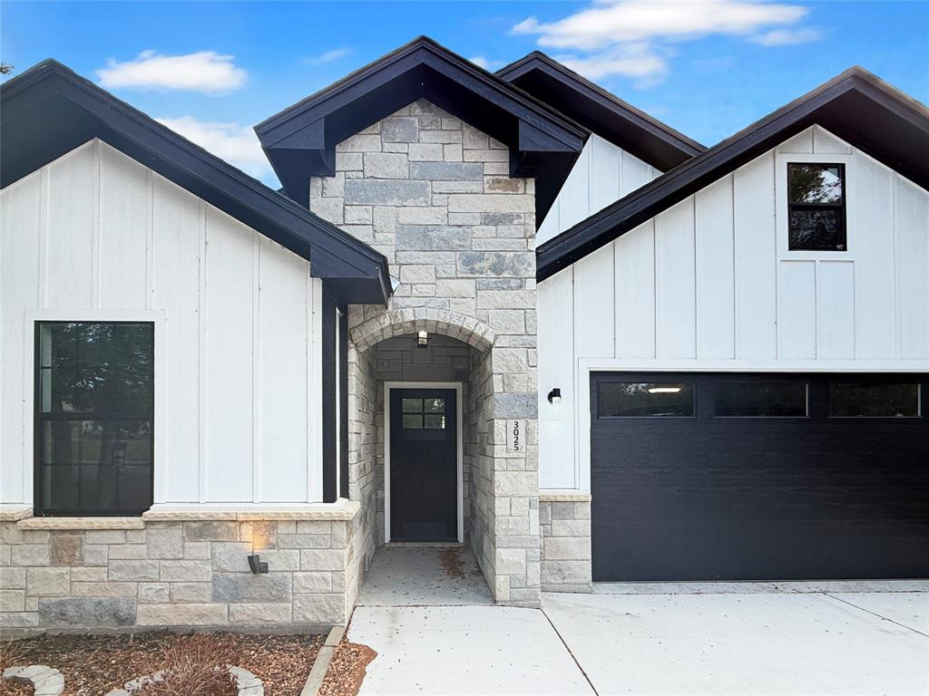 Exterior featuring board and batten siding, masonry facade, dual-pitched roofline, contrast trim, and a concrete driveway Exterior featuring board and batten siding, masonry facade, dual-pitched roofline, contrast trim, and a concrete driveway