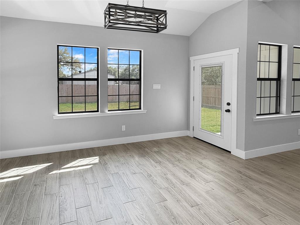 Vaulted ceilings, wood-finish flooring, rectangular windows with black frames, and a geometric metal chandelier Vaulted ceilings, wood-finish flooring, rectangular windows with black frames, and a geometric metal chandelier