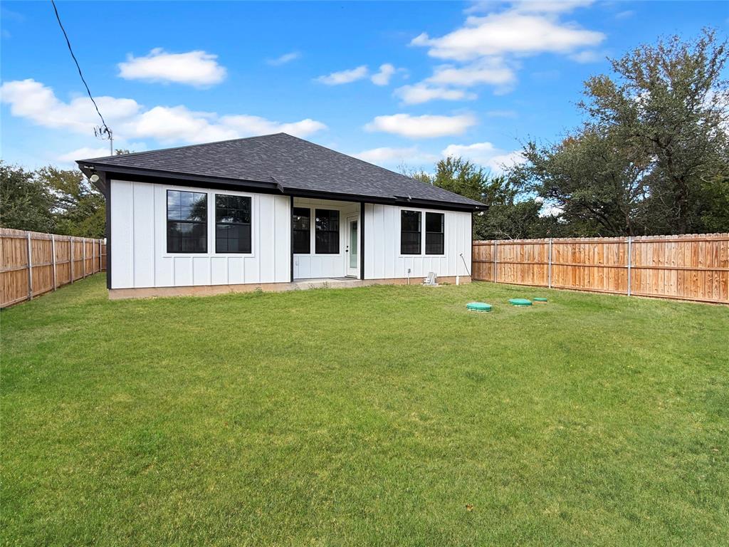 Backyard featuring a grass lawn, full-perimeter wood privacy fencing, board-and-batten siding, and a hipped roof Backyard featuring a grass lawn, full-perimeter wood privacy fencing, board-and-batten siding, and a hipped roof