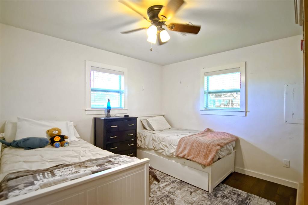 Neutral interior featuring two multi-pane windows with trim, hard-surface flooring, and a ceiling-mounted light fixture with a three-blade fan