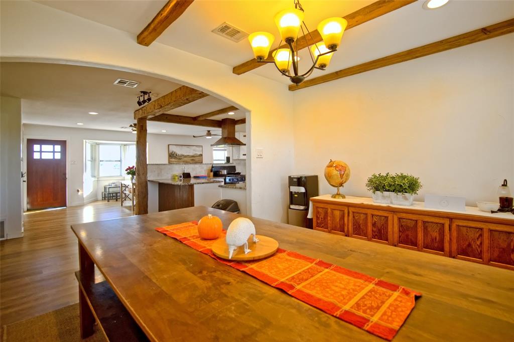 Exposed timber ceiling beams, wood-finish flooring, multi-light chandelier, and arched architectural detailing