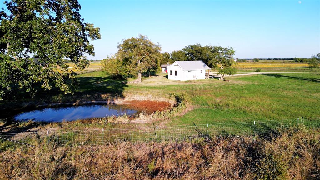 Expansive rural acreage featuring a detached structure, a natural pond, mature trees, and wire perimeter fencing Expansive rural acreage featuring a detached structure, a natural pond, mature trees, and wire perimeter fencing