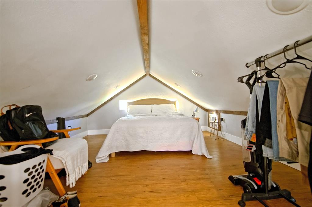 Vaulted ceiling featuring exposed wood beam accents and recessed lighting, finished with wood-finish flooring