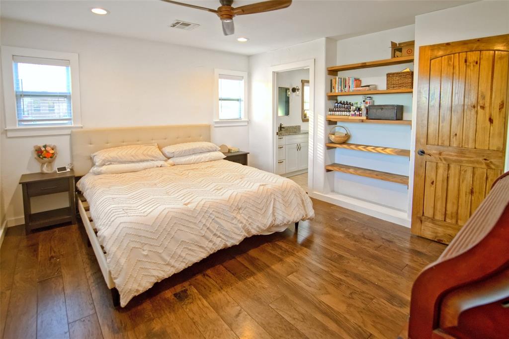 Wood-finish flooring, built-in recessed wood shelving, arched wood door, and recessed lighting
