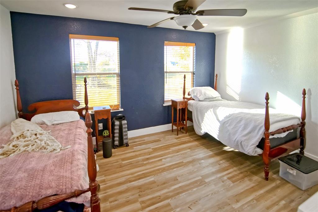 Wood-finish flooring, accent wall, ceiling fan, and dual windows