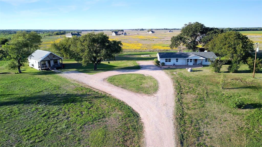 Expansive acreage featuring two detached structures, a gravel circular driveway, mature trees, and open pasture land Expansive acreage featuring two detached structures, a gravel circular driveway, mature trees, and open pasture land