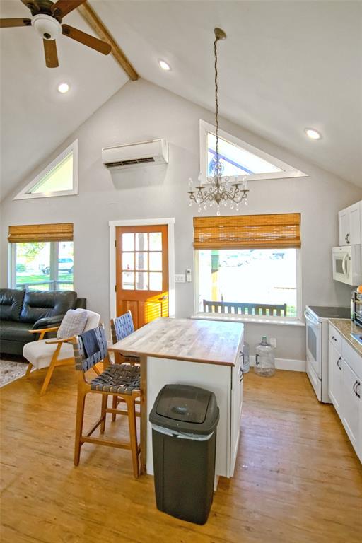 Vaulted ceiling featuring exposed wood-finish beams, recessed lighting, a chandelier, wood-finish flooring, and a wall-mounted climate control unit