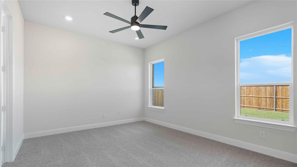 Neutral-toned interior featuring carpeted flooring, two double-pane windows, and a matte black ceiling fan with integrated lighting