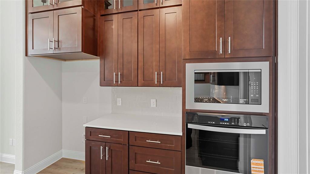 Dark wood-finish cabinetry featuring shaker-style doors, stone-surface countertops, and stainless steel built-in microwave and oven combination
