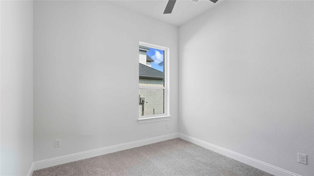 Neutral interior space featuring crisp white walls, carpeted flooring, a single-hung window, and a ceiling fan