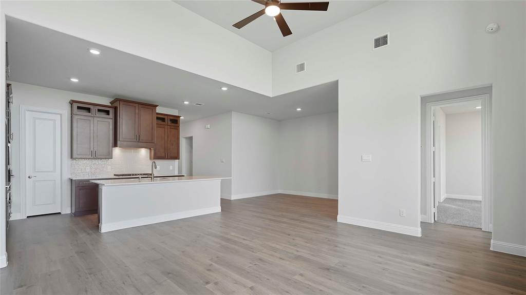 Open-concept interior featuring vaulted ceilings, wood-finish flooring, recessed lighting, and a kitchen equipped with wood cabinetry and a central island