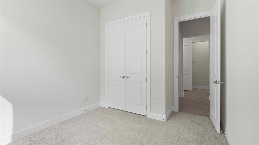 Neutral-toned carpeting, white two-panel closet doors with satin nickel hardware, and a matching interior door with a lever handle