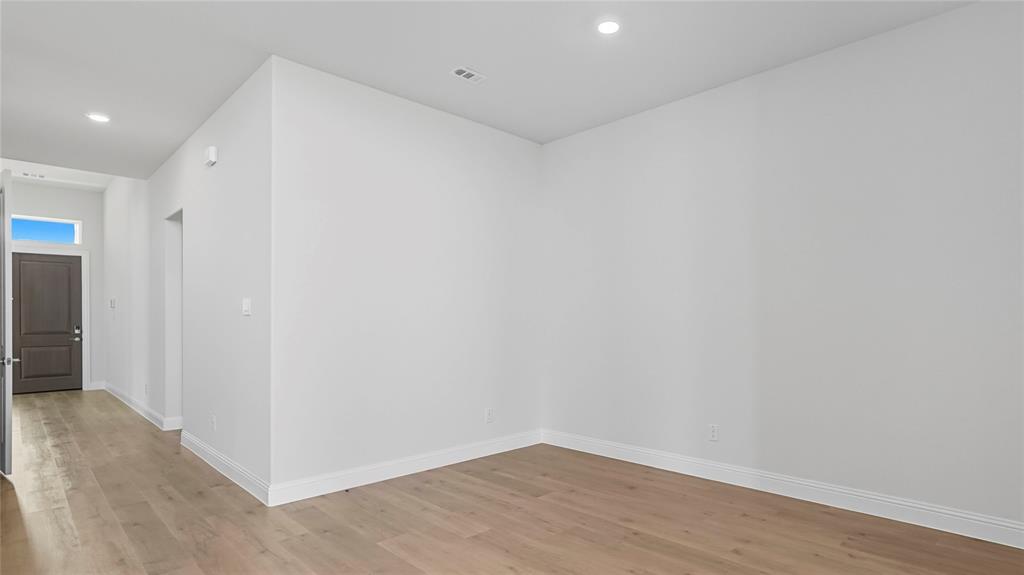 Interior space featuring wood-finish flooring, recessed lighting, and a dark-toned paneled entry door with a rectangular transom window