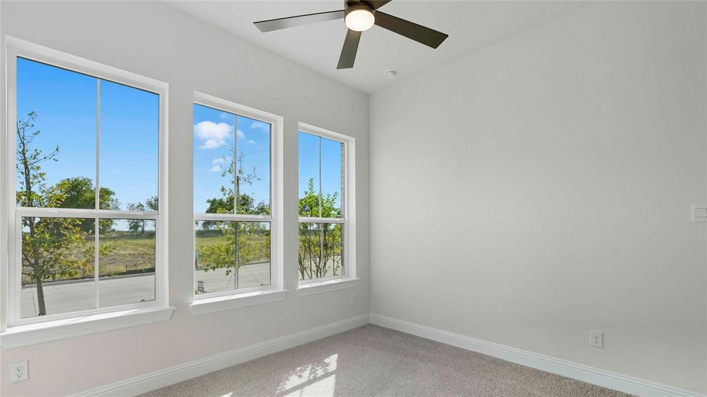 Room featuring neutral-toned carpeting, three large multi-pane windows, and a matte black ceiling fan with integrated lighting