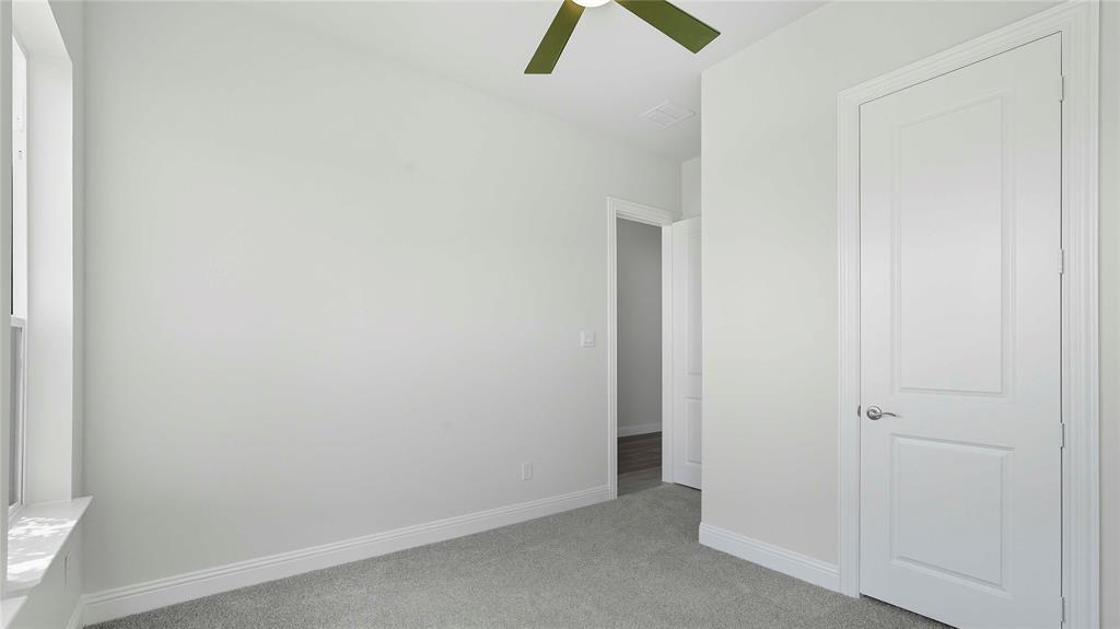 Neutral-toned interior featuring wall-to-wall carpeting, a multi-panel interior door, and a ceiling fan
