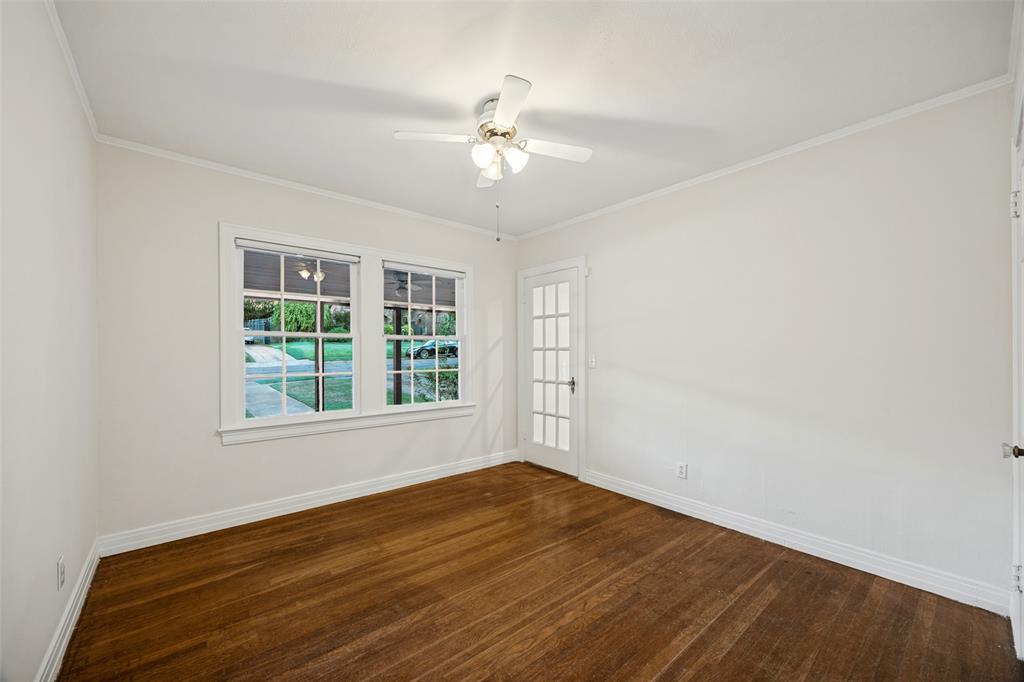 Room interior featuring wood-finish flooring, white walls, a ceiling fan with integrated lighting, dual-pane windows, and a glass-paneled exterior door