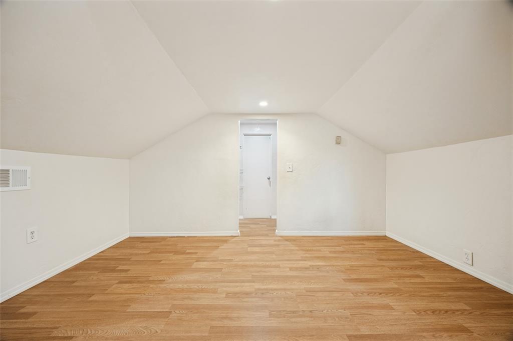 Interior room featuring vaulted ceilings, wood-finish flooring, and a single recessed light fixture