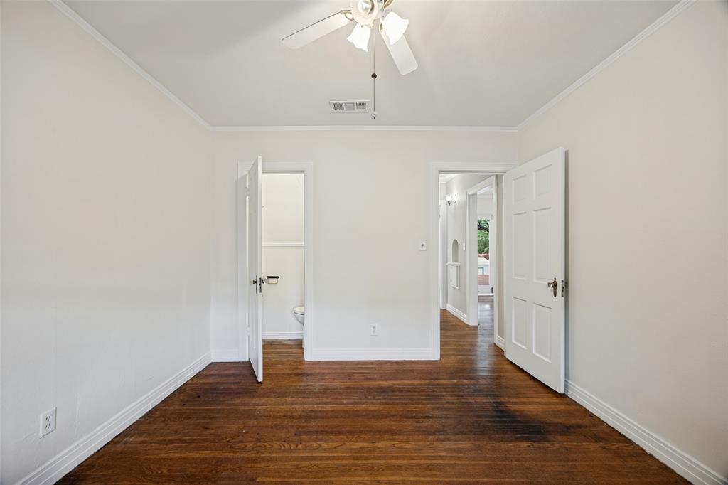 Room featuring wood-finish flooring, white six-panel interior doors, and a ceiling-mounted light fixture with a fan