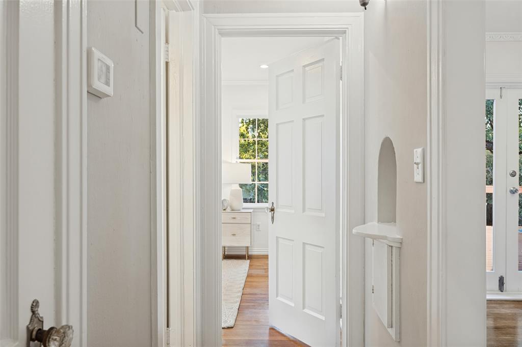 Six-panel interior door with traditional hardware, arched architectural wall niche, wood-finish flooring, and double-paned multi-light window