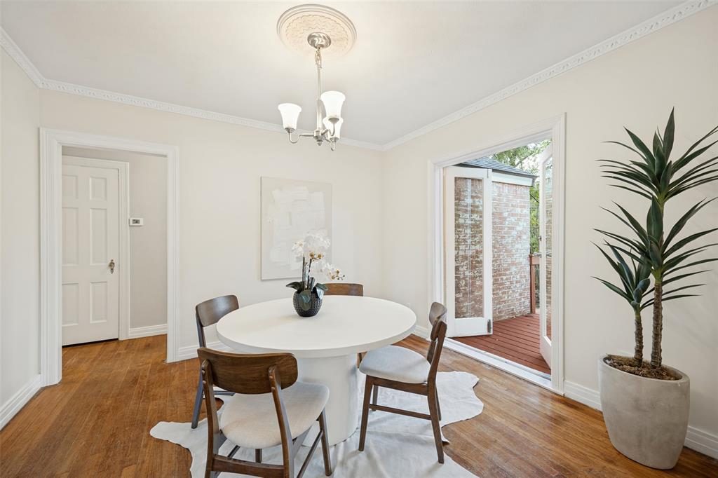 Wood-finish flooring, crown molding, ceiling medallion with a three-light chandelier, and glass-paneled double doors opening to a wood-decked outdoor space