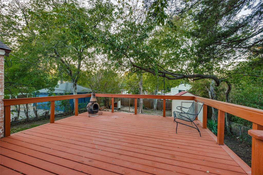 Elevated wood-plank deck featuring a perimeter railing and mature tree canopy