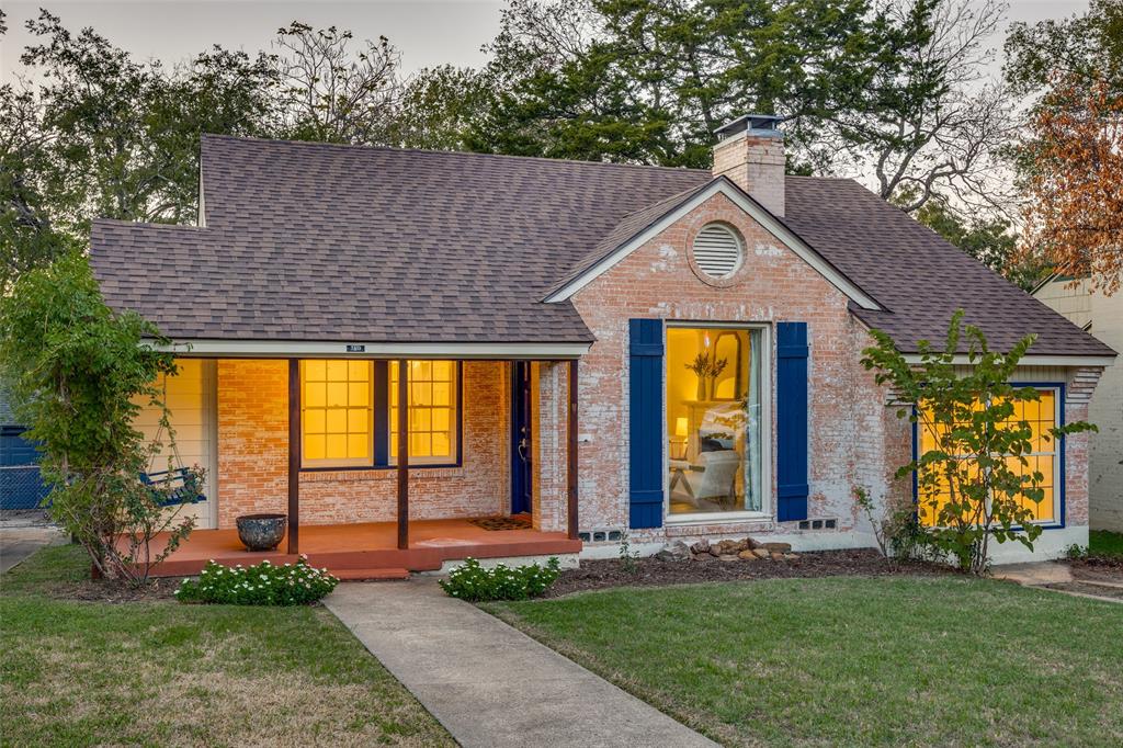 Brick exterior featuring a covered front porch, asphalt shingle roofing, decorative window shutters, and a circular gable vent