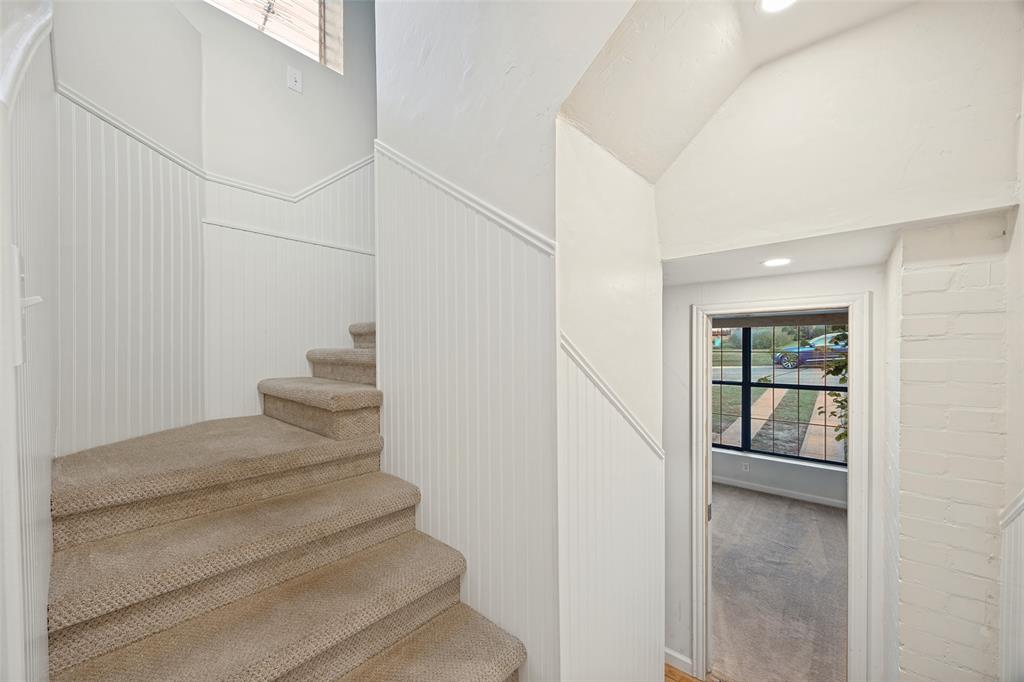 Staircase featuring wall-to-wall carpeting and beadboard wainscoting, accented by a painted brick wall and recessed lighting